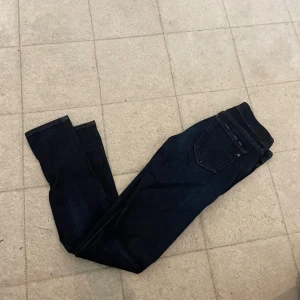 Replay Hyperflex mörkblå jeans - Säljer ett par mörkblå Replay Hyperflex jeans med klassisk femficksdesign. Jeansen är tillverkade i stretchigt denimtyg som ger extra komfort och rörelsefrihet. Perfekta för dig som gillar en stilren look med modern passform.