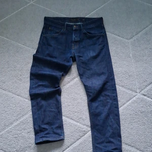 Mörkblå jeans från Massimo Dutti - Snygga mörkblå jeans från Massimo Dutti med klassisk femficksdesign och raka ben. Jeansen har orange kontrastsömmar och är tillverkade i bomullsdenim. Perfekta för dig som gillar stilrena och tidlösa jeans.