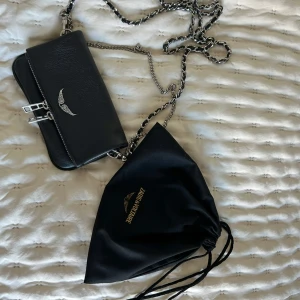 Svart axelväska Zadig & Voltaire skinn - Snygg svart axelväska från Zadig & Voltaire i äkta skinn med silverfärgade metalldetaljer och kedjerem. Väskan är i mycket bra skick.