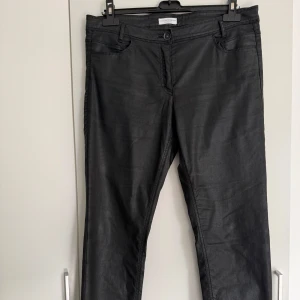 Charles Vögele Collection svarta byxor, storlek 42 - •Ett par svarta byxor med fickor fram och bak.  •Byxorna har en lätt glansig yta som ger en cool look och är tillverkade i ett stretchigt material för extra komfort.  •Klassisk knapp och dragkedja framtill samt bälteshällor. •Mycket bra skick och bra kvalité. •Djurfritt och rökfritt hem.