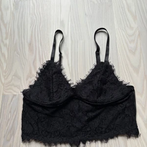 Svart spetsig linnetopp från SHEIN - Svart linnetopp från SHEIN med tunna justerbara axelband och spetsdetaljer längs kanterna. Toppen har en croppad passform och är lite cropad, skick är jätte svårt att sätta då alla tycker olika men enligt mig är de ett bra skick