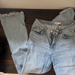 Ljusblå jeans med fransiga benslut - Säljer ett par ljusblå jeans från Gina Tricot med raka ben och fransiga benslut. Klassisk femficksmodell med knapp- och dragkedjegylf. Perfekta för en avslappnad och trendig look.