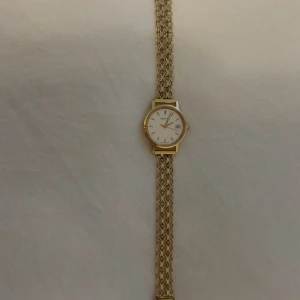 Guldfärgad Longines armbandsur - Stilren armbandsklocka från Longines med vit urtavla, datumvisning och guldfärgat armband i länkdesign. Klockan har en klassisk rund form och elegant spänne med stämplar. Perfekt accessoar för dig som gillar tidlös design.