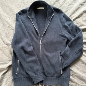 Mörkblå kofta från MNG - Säljer en stilren mörkblå cardigan från MNG med dragkedja framtill och två praktiska fickor med dragkedjor. 