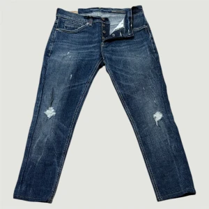 Dondup george - Snygga dondup george jeans i mörkblå tvätt med slitningar och trasiga detaljer på benen. Klassisk femficksmodell med knappgylf och kontrastsömmar. Jeansen har en slim passform och är tillverkade i slitstarkt denimtyg. Tveka inte på att höra av er