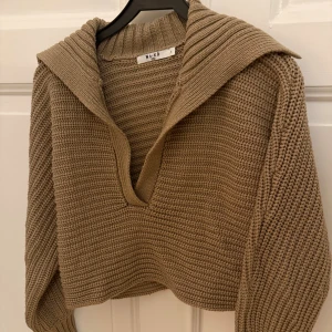 Brun stickad tröja från NA-KD - Säljer en brun stickad tröja från NA-KD i storlek S. Tröjan har en bred krage, v-ringad hals och grovstickad struktur. Super snygg och skön men kommer ej till användning, endast använd 1-2 gånger!