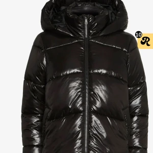 Svart pufferjacka med huva - Säljer en svart, glansig pufferjacka med stor huva och dragkedja framtill. Jackan har en schysst oversized passform och är tillverkad i syntetmaterial. Perfekt för kalla dagar och har en cool, modern look som funkar till jeans och sneakers. Är en reva på ena armen som har blivit lagad du får be om bild på de