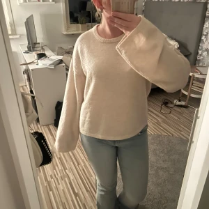 Beige stickad tröja med vida ärmar - Mysig beige stickad tröja med rund halsringning och extra vida, långa ärmar. Perfekt för dig som gillar en chill och avslappnad stil. Passar snyggt till jeans eller kjol och är superenkel att styla till olika looks.