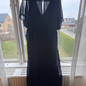 Marinblå långklänning från Bubbleroom - Snygg marinblå långklänning från Bubbleroom med v-ringning och transparenta, fladdriga korta ärmar. Klänningen har ett lätt och luftigt tyg som ger en elegant känsla. Normal i storleken, endast använd 1 gång. 