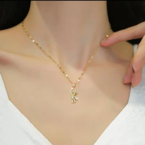 Snygg halsband med glittrig nalle i rostfritt stål med 18k guldpläterad  - Supersött halsband i 18k guldpläterad med en glittrig nalle som hängsmycke. Kedjan har små platta länkar och nallen är täckt av gnistrande stenar med svarta ögon. Ovanför nallen sitter en stjärnformad detalj med en klar sten i mitten. Perfekt för dig som gillar unika och söta smycken.