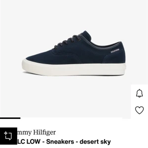 Mörkblå sneakers Tommy Hilfiger - Snygga mörkblå sneakers från Tommy Hilfiger med låg profil och rund tå. Skorna har vit platt sula, snörning med metallöglor och är tillverkade i mocka för en soft känsla. Perfekt för dig som gillar stilrena och klassiska sneakers.