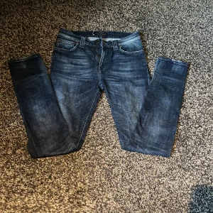 Blå nudie jeans - Snygga mörkblå jeans från Nudie Jeans i modellen skinny med klassisk femficksdesign och dragkedja. Jeansen har en medel passform.