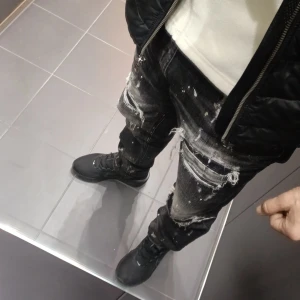 Supply & Demand svarta jeans med slitningar - Svarta jeans från Supply & Demand med coola slitningar och färgstänk över hela byxorna. Modellen har raka ben och flera rejäla hål och trasiga detaljer på framsidan för en edgy streetstil. Jeansen har klassisk femficksdesign och är tillverkade i jeansmaterial. Storlek 32 sitter perfekt på mig använt dom i 2 månader  helt och hållet rena o fräscha o fortfarande som nya . Säljes för 500