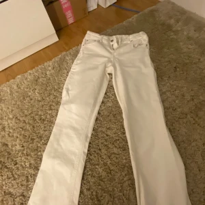 Vita jeansbyxor från Gina Tricot - Snygga vita jeansbyxor från Gina Tricot i storlek 152. Klassisk femficksmodell med flared ben och silverfärgade knappar bak.