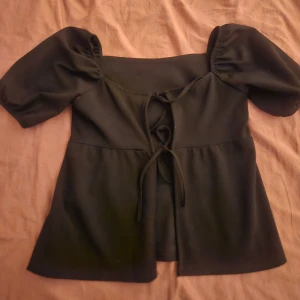 Svart blus med puffärm och knyt - Svart blus med korta puffärmar och rosetter som man kan knyta själv tajt eller löst. Lite stor I storleken jag skulle säga att den är i size small. Den är från Missäy. Jag säljer för den är lite för stor I storleken för mig och jag tycker inte att den passar mig, köpt förra året men bara använd kanske en eller två gånger❤️