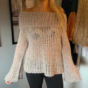 Beige offshoulder stickad tröja - Säljer en beige, grovstickad offshoulder-tröja med vida ärmar. Tröjan har en snygg, öppen axel-design och är stickad i ett luftigt garn som ger en cool och avslappnad vibe. Perfekt att styla med jeans eller kjol för en trendig look.