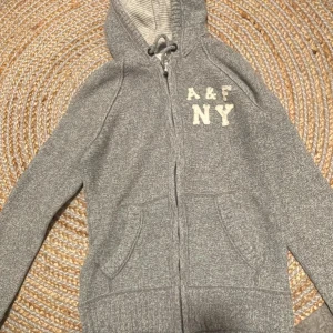 Grå hoodie från Abercrombie & Fitch - Säljer min sjuktttt feta Abercrombie tröja i stl L.  Den är perfekt nu till kallare dagar när man vill vara varm. Den har inga hål eller andra fel vilket är varför priset är som det är. Dock är det aldrig fel att lägga PRISFÖRSLAG ☺️.