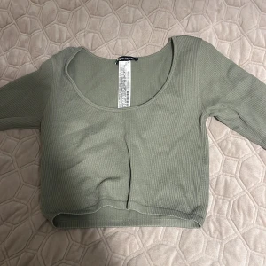 Grön croppad ribbad topp från Zara - Snygg croppad topp från Zara i en ljusgrön nyans. Toppen har lång ärm, rundad halsringning och är ribbad för extra stilpoäng. Perfekt att matcha med höga jeans eller kjol för en chill look. Stretchig matrial passar även som s