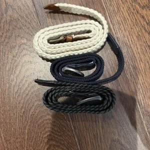 3-pack flätade bälten i olika färger - Säljer tre snygga flätade bälten i beige, marinblått och svart. Alla har silverfärgat spänne och detaljer i läderimitation. Perfekta för att ge en casual och stilren touch till din outfit. Bältena är gjorda i ett mjukt, stickat material som är flexibelt och bekvämt.