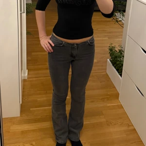 Grå bootcut jeans med låg midja från H&M - Snygga grå jeans med bootcut passform och låg midja från H&M. Klassisk femficksmodell med dragkedja och knapp framtill. Jeansen har en rak siluett upptill och lätt utsvängda ben, vilket ger en cool retrovibe. Perfekta till sneakers eller boots.