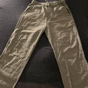 Oliv gröna linnebyxor från H&M med snörning - Snygga olivgröna linnebyxor från H&M i storlek 158. Byxorna har elastisk midja med snörning, raka ben och praktiska fickor fram samt en bakficka. Perfekta för chill dagar och sommarhäng. Nypris 200kr
