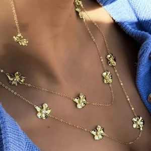 Guldigt halsband med blommor - Supersnyggt halsband i guldton med flera blommor längs kedjan. Blommorna har en glittrande detalj i mitten som ger extra lyxig känsla. Perfekt för att lyfta din outfit med en unik och trendig touch. Kedjan är tunn och smidig, och blommorna är jämnt placerade för en cool look. PRIS KAN DISKUTERAS 