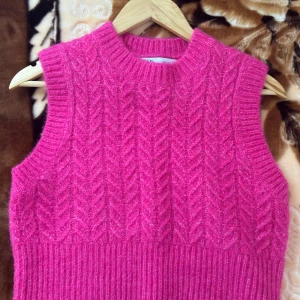 Stickad rosa väst från Zara - En stickad väst från Zara i en stark rosa färg. Västen har ett snyggt kabelstickat mönster och ribbade kanter vid hals och ärmhål. Perfekt att styla över en skjorta eller t-shirt för en trendig lager-på-lager-look.