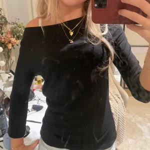 Svart offshoulder tröja - Snygg svart offshoulder tröja med trekvartsärm. Tröjan har en smickrande passform och är perfekt för dig som gillar en stilren look med lite edge. Materialet känns mjukt och följsamt mot kroppen. Passar dig som vill ha en enkel men trendig topp.