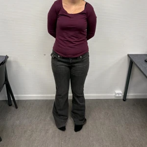 Grå bootcut jeans från True Religion - Snygga grå jeans från True Religion med bootcut passform och klassiska fickor med lock och silverknappar bak. Jeansen har låg midja och är tillverkade i stretchigt denim för en bekväm känsla. Perfekt för dig som gillar en cool och avslappnad stil.