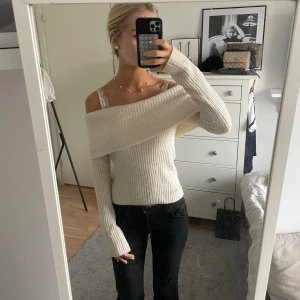 Offshoulder ribbad stickad tröja - Snygg offshoulder stickad tröja i ljus beige färg med ribbad struktur. Tröjan har långa ärmar och sitter normal i passformen. Perfekt för dig som gillar en trendig och stilren look med lite extra edge.