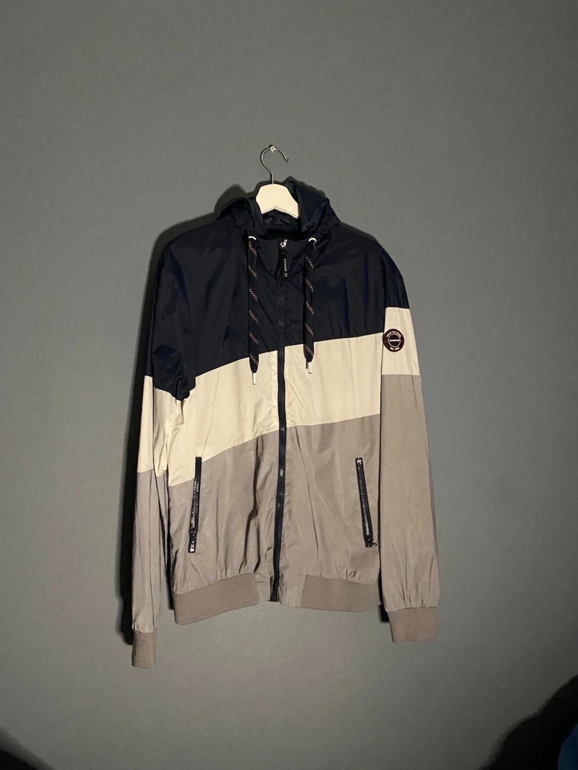 Vindjacka från Outernational i navy och beige