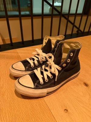 Converse Sneakers All Star svart - Klassiska Converse Chuck Taylor All Star high tops i svart canvas med vita snören och tåhätta. 