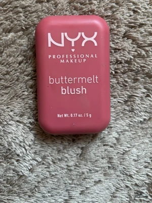 NYX buttermelt blush rosa - NYX buttermelt blush i en snygg rosa nyans. Kommer i en rektangulär plastförpackning med lock och har ett mönstrat pressat puder. Perfekt för att ge kinderna en fräsch och pigg färg. Innehåller 5 g produkt.