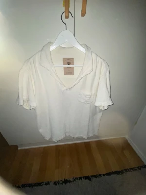 Vit frotté polotopp från OAS - Säljer en OAS T-shirt med lång krage inför sommarn. Har en nice vit färg och är väldigt bekväm.