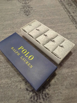 Gråa strumpor från Polo Ralph Lauren - Säljer ett 5-pack gråa strumpor från Polo Ralph Lauren. Strumporna har den klassiska broderade loggan i svart och är tillverkade i mjuk bomullsmix. Perfekta för dig som vill ha stilrena och bekväma strumpor till vardags.