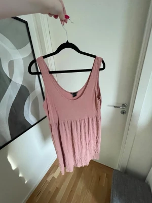 Rosa klänning från H&M - Rosa klänning från H&M Basic i storlek L. Klänningen har breda axelband och har en avslappnad passform med rynkad midja