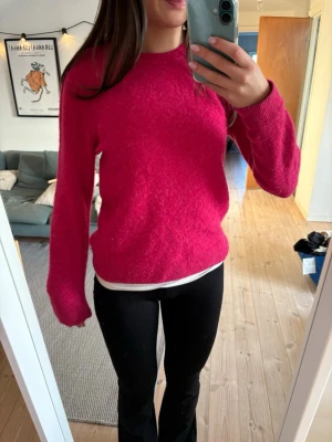 Mörkrosa stickad tröja - Säljer en mysig mörkrosa stickad tröja med rund halsringning och långa ärmar. Tröjan har en enkel, klassisk design och är perfekt för kyligare dagar. Passformen är normal och materialet känns mjukt och fluffigt.