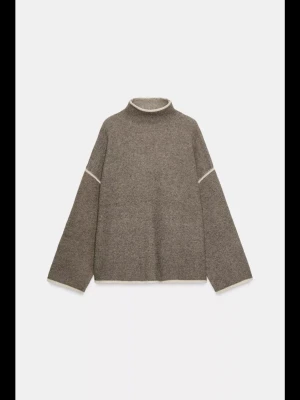 Beige stickad polotröja med vita detaljer - Säljer en beige stickad polotröja med vita kontrastsömmar vid hals, ärmar och nederkant. Tröjan har en loose passform och långa ärmar, perfekt för lager-på-lager under kyliga dagar.