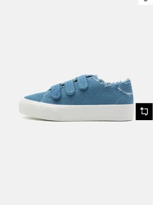 Blå sneakers med kardborre och rå kant - Snygga blå sneakers i denim-look med tre kardborreband och vit platt sula. Skon har en rå, fransig kant upptill som ger en avslappnad vibe. Perfekt till jeans eller shorts för en chill stil. Använd en gång