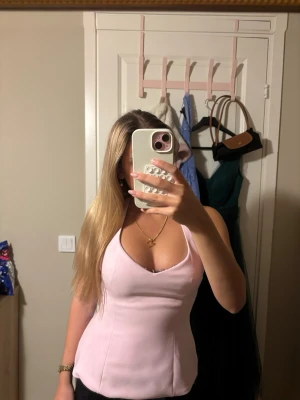 Ljusrosa korsettopp från Zara - Supersnygg ljusrosa korsettopp med breda knytband i nacken och öppen rygg. Toppen har en figurnära passform och är ärmlös, perfekt för att lyfta vilken outfit som helst. Materialet känns mjukt och har en lätt glans.