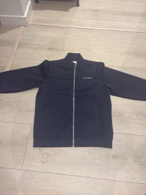 svart/mörkblå zip/tunn jacka nyskick använd 1-2 gånger - Säljer en svart/mörk blå zip/tunn jacka från Les Deux med stilren design och diskret logga på bröstet. Jackan har hel dragkedja framtill, två fickor och en klassisk krage. Perfekt för dig som vill ha en clean look till vardags. Pris kan diskuteras