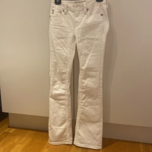 Vita bootcut jeans Miss Me strl 25 - Snygga vita jeans från Miss Me i bootcut-modell. Byxorna har coola bakfickor med paljett- och broderidetaljer i silver och guld. Klassisk femficksdesign och silverfärgade nitar. Perfekta för dig som vill sticka ut lite extra.