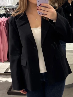 Svart kavaj - Klassisk svart kavaj med enkelknäppning och två fickor framtill. Rak passform och helfodrad insida. Perfekt till jeans eller kjol för en clean och stilren look. Materialet är mjukt och känns bekvämt mot huden. Helt ny, aldrig använd! Den är i storlek 42 men sitter som M/38