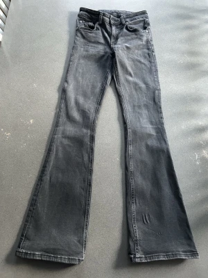 Grå lågmidjade utsvängda jeans storlek XS full length - Lager 157 low boot storlek XS full length.  Använt skick men har betydligt mer att ge. Slitningar nere vid fötterna bak, rynkning i tyget nere på ena benet och sliten lapp vid midjan. Låg midja, low waist, boot cut.  Tvättar utan sköljmedel och torktumlar inte kläder. 