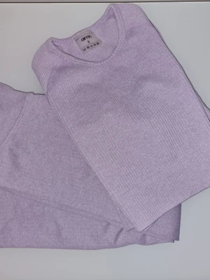 Träningsset från Aim'n  - Set med en långärmad tröja och ett par trekvarts leggings från Aim'n. Båda plaggen har en ribbad textur och är i färgen syrenlila/violet. Helt nya och är endast testade.