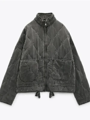 Populär grå quiltad jacka - Quiltad jacka i mörkgrå färg med snygg snörning nedtill och två stora fickor framtill. Jackan har en rak, loose passform och dragkedja hela vägen upp till den höga kragen. Materialet är mjukt och ger en cool vibe. Är osäker på storlek men tror att det är en XS men passar en S också💞pris går att diskutera! 