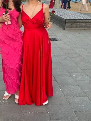 Röd långklänning - Jag säljer en superfin röd långklänning med smala dubbla axelband och v-ringad omlott framtill. Klänningen har ett flytande fall och är perfekt för speciella tillfällen som till exempel balen eller studenten. Använd en gång på en bal. Klänningen köptes på jolies bridal i Malmö och är en storlek 8. Men hör gärna av er om ni undrar över exakta mått💓
