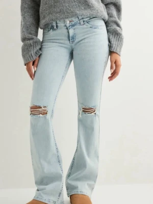 Ljusblå bootcut jeans med slitningar - Säljer ett par ljusblå jeans med bootcut passform och slitna hål över knäna. Jeansen har klassisk femficksdesign och coola broderade detaljer i rött på bakfickorna. Perfekta för dig som gillar en avslappnad och trendig stil. Jeansen är helt nya och jag har bara testat dom på.