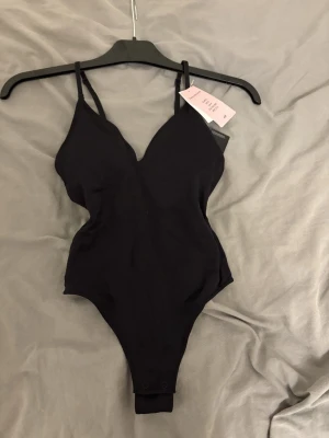 Hm body - Snygg och mycket populär svart body från H&M, nu slutsåld i butik. Bodyn är helt ny, endast provad, och prislappen sitter kvar.  Modellen har justerbara axelband för perfekt passform samt inbyggda vadderade kupor (pads) som enkelt kan tas ut vid behov. Ger ett fint stöd och en smickrande silhuett. Skön, stretchig kvalitet och stringmodell, vilket gör den perfekt både under kläder och som topp till jeans eller kjol. Hör av dig om du har frågor🥰
