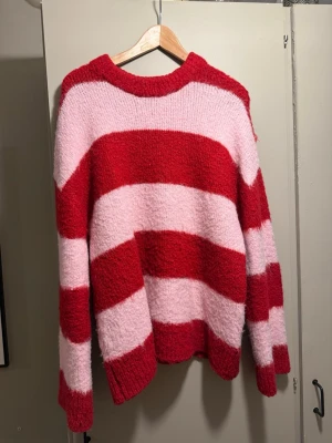 Randig stickad tröja Gina Tricot - Säljer en mysig stickad tröja från Gina Tricot i storlek S. Tröjan har breda ränder i rött och ljusrosa, rund halsringning och lång ärm. Perfekt för dig som vill ha en färgglad och skön vardagslook.